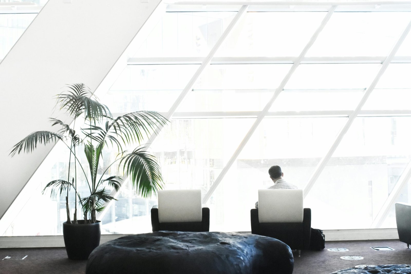 Spacious modern lounge with minimalist decor, featuring large windows and stylish seating.